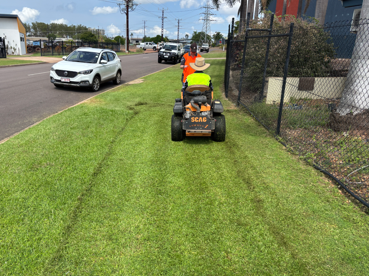 Worker mowing grass near road